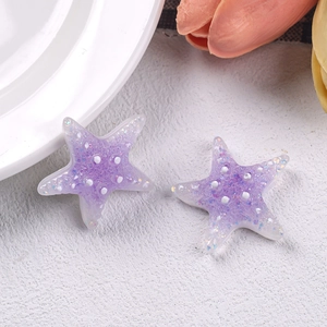 Macro shot of purple resin starfish charms with glitter sequins and white polka dots