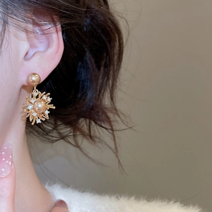 Dettaglio di modella con orecchini a stella in oro con perle champagne e piccoli cristalli