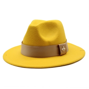 Detail of yellow wool fedora hat featuring khaki band and golden bee metal emblem