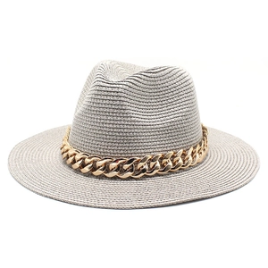 Close-up of light gray straw fedora hat featuring a chunky gold acrylic chain accessory