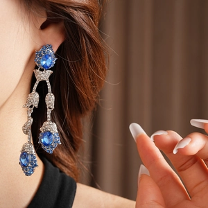 Silver vintage flower tassel earrings with blue and white rhinestones on a model