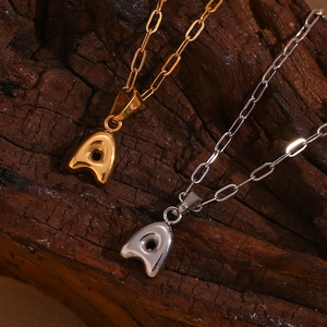 Detail of gold and silver letter A pendants on clip chain over dark wood background