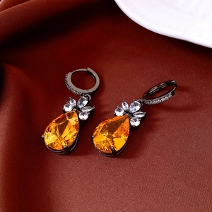 Detail of vintage teardrop earrings with amber zircon on elegant dark red silk fabric