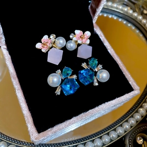 Detail of pink flower and blue crystal earrings with pearls in a luxury jewelry box