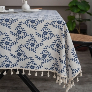 Close-up of linen-cotton tablecloth featuring blue floral patterns and beige tassels