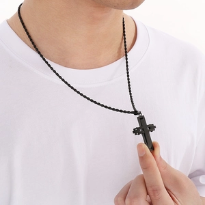 Close-up of black stainless steel cross pendant and twist chain on a male model