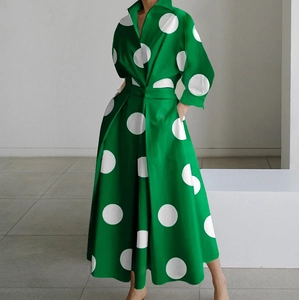 Dettaglio di un abito verde a maniche lunghe con pois bianchi e taglio in vita elegante