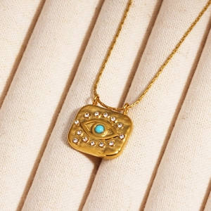 Detail shot of a square evil eye pendant with 18k gold plating and turquoise stone