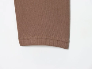 Macro detail of brown knit fabric showing precision double needle stitching and texture