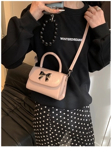 Mini borsa a tracolla rosa con chiusura a fiocco dorata indossata sulla spalla