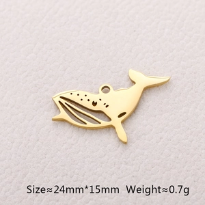 Macro detail of a golden whale-shaped stainless steel pendant on textured paper