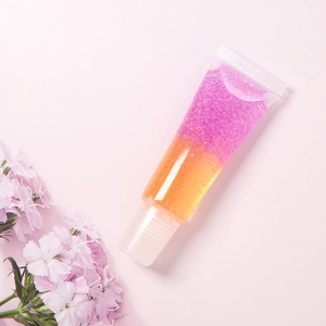 Primer plano de brillo labial de doble capa naranja y morado con purpurina en tubo
