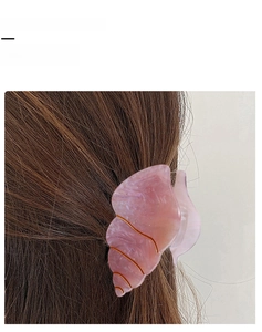 Pink marble conch hair claw clip with gold accents shown on dark brown hair