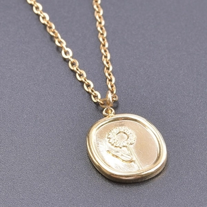Detailed close-up of a vintage golden oval sunflower pendant on a stainless steel chain