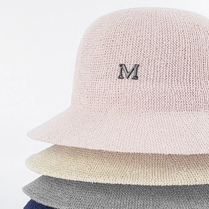 Detailed view of the fine knit texture and metal M logo on stacked woven bucket hats