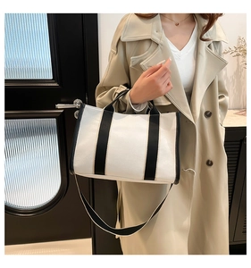 Detail view of contrast canvas tote bag showing the black handles and adjustable shoulder strap