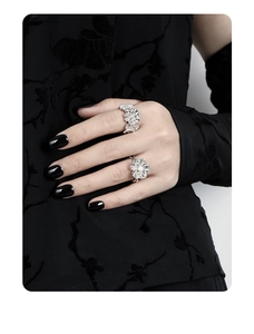 Detailed view of silver flower rings with textured petals on a model's hand