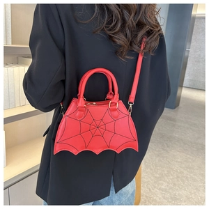 Detailed shot of a red bat-wing shaped handbag with spider web stitching on model