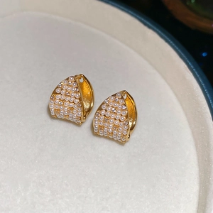 Detailed close-up of French style gold earrings with pearls and zircons in a jewelry box