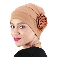 Close-up of brown turban hat featuring a decorative large fabric rose on the side