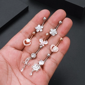 Macro shot of zircon and opal belly rings with butterfly and heart charms on palm