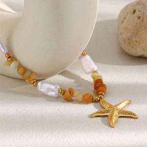 Detail of 18K gold-plated starfish pendant with white pearls and orange crystal stones