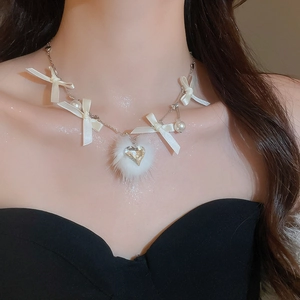 Detail of elegant ribbon bow necklace with white pom-pom and heart crystal on model