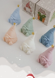 Top view of colorful Christmas gnome scented candles with bells and festive gift boxes