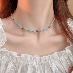 Detail of bohemian choker necklace with turquoise tube beads and red round beads