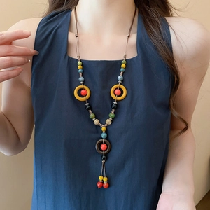 Detailed close-up of handmade ethnic ceramic bead necklace with colorful tassels on model