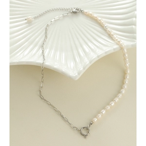 Dettaglio collana con perle d'acqua dolce e catena d'argento su piatto a conchiglia