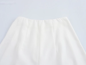 Dettaglio dei pantaloni bianchi a vita alta con pince sartoriali e tessuto di alta qualità