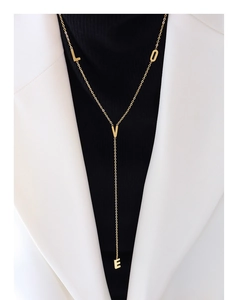 Dettaglio della collana lunga a Y dorata con ciondoli LOVE su un maglione nero