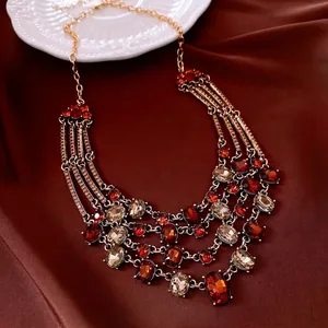 Vintage multi-layer gold necklace with red and champagne gemstones on red satin