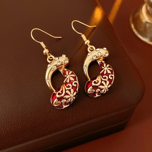 Close-up of vintage gold earrings with red enamel and clear zircon on a leather box