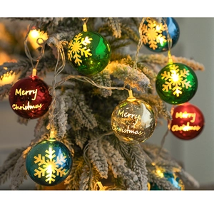 Close-up of multicolor Merry Christmas light balls hanging on snowy pine tree branches