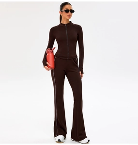 Detail of slim fit brown yoga set with zip-up top and white striped flared pants