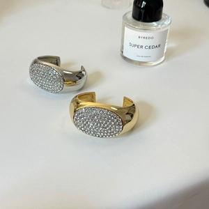 Detail von klobigen Gold- und Silberarmreifen mit dichtem Strassbesatz und Metallglanz