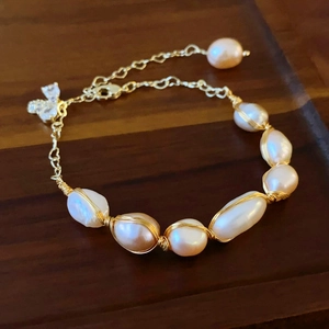 Detailed close-up of gold-plated baroque pearl wrap bracelet with heart-shaped charm