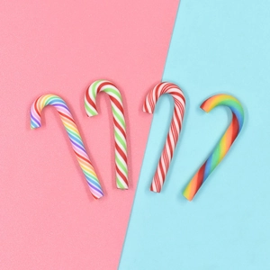 Set of four colorful polymer clay candy cane charms for DIY crafts on pink and blue background