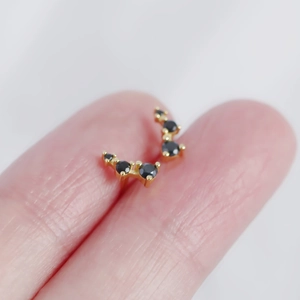 Macro shot of curved gold S925 silver stud earring with five black sparkling zircons