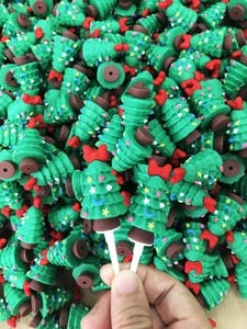 Close-up of bulk green silicone Christmas tree cake toppers with red bows and plastic sticks