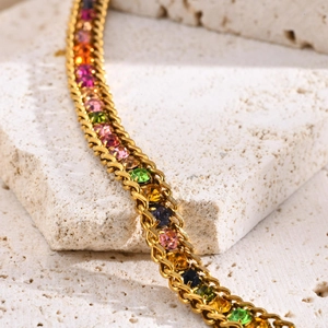 Macro detail of gold stainless steel bracelet featuring vibrant rainbow zircon stones