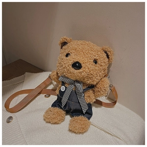Detail of cute light brown plush teddy bear bag in blue denim overalls and checkered bowtie