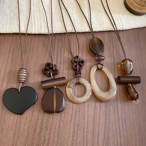 Detailed view of vintage resin heart and geometric pendants on a rustic wood background