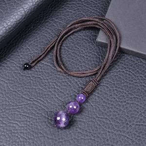 Macro shot of three natural purple amethyst beads on a brown braided rope necklace