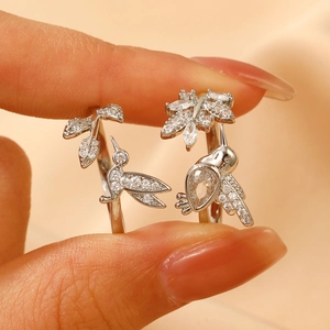 Macro shot of silver open ring set with hummingbird and zircon leaf details