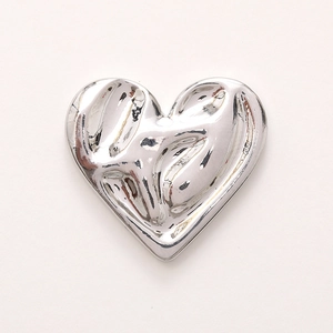 Macro de un accesorio de corazón de metal plateado con textura líquida irregular
