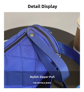 Close-up of quilted royal blue bag with metal rivet zipper pull and stitch detail