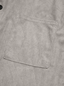 Macro shot of grey corduroy jacket texture featuring a square pocket and neat stitching